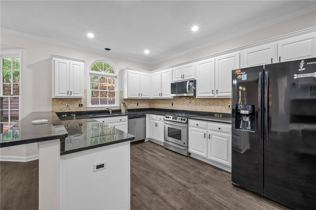 2250 Chickering Court Cumming, GA 30041 - Photo 5 of 25 a kitchen with kitchen island granite countertop a stove a sink a refrigerator and cabinets