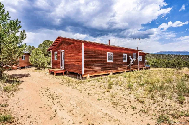 a view of a chairs and table in the patio next to a yard