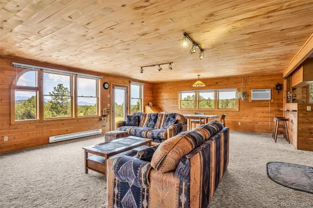 a living room with furniture a ceiling fan and a large window