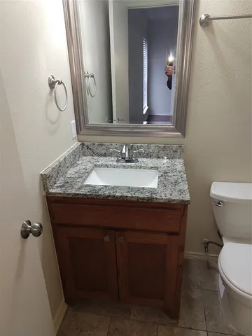 a bathroom with a granite countertop sink a toilet and a mirror