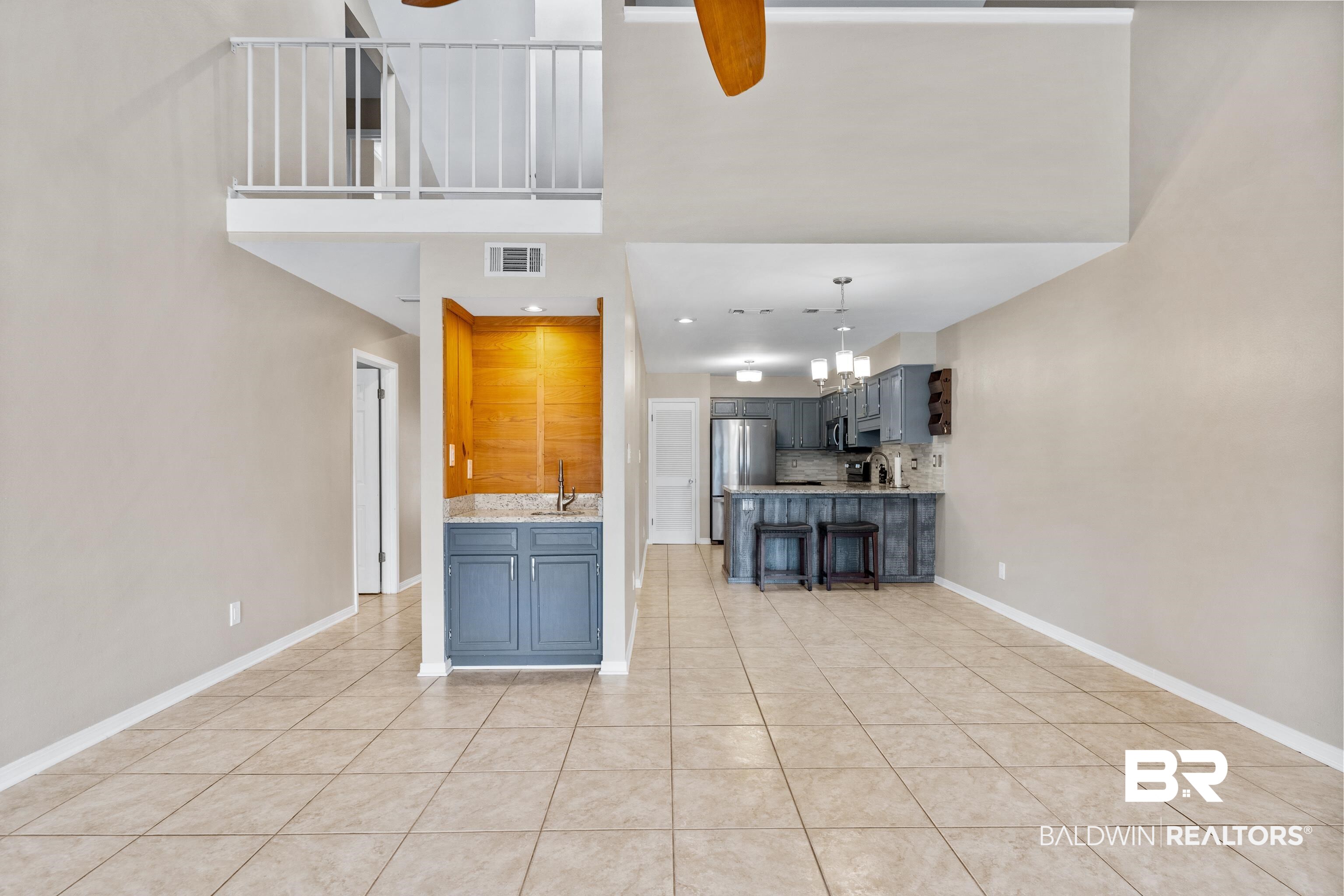 1701 Regency Road, Unit 111 Gulf Shores, AL 36542 - Photo 9 of 29 Kitchen featuring light tile patterned flooring, sink, ceiling fan with notable chandelier, backsplash, and stainless steel fridge