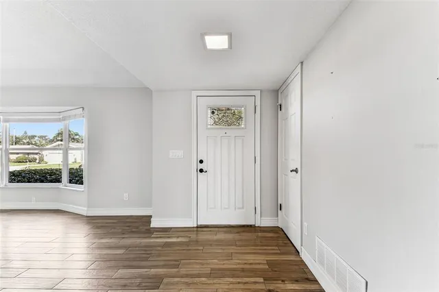 a view of an empty room with wooden floor and a window
