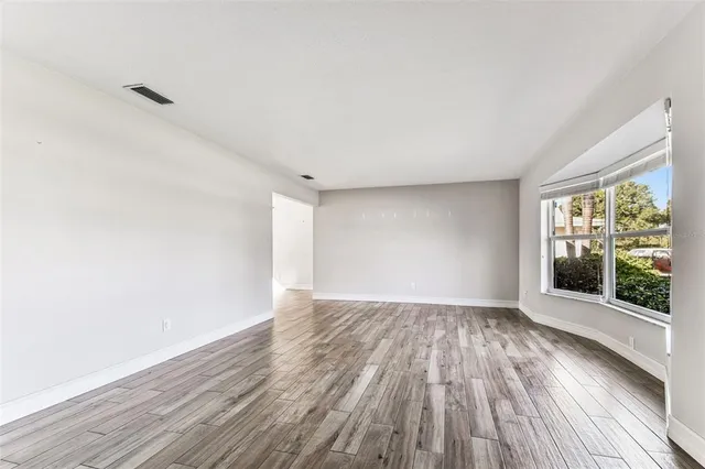 a view of an empty room with wooden floor and a window