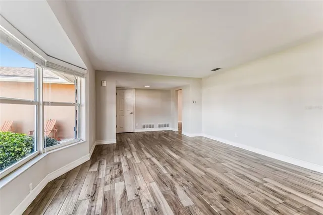 a view of an empty room with wooden floor and a window