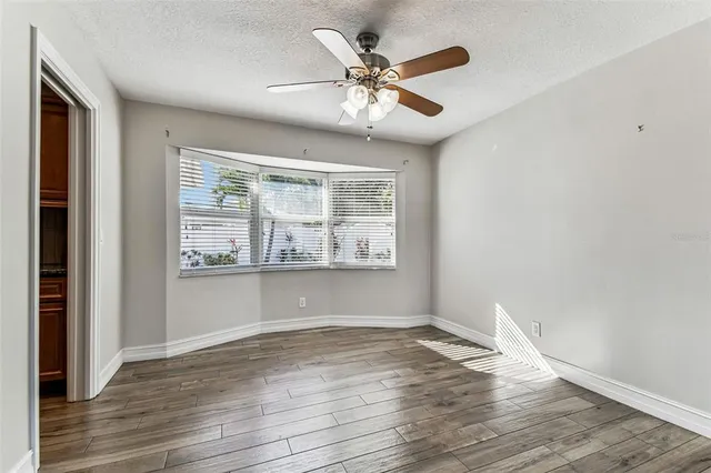 a kitchen with stainless steel appliances granite countertop a stove top oven a sink dishwasher a microwave oven and a dining table with wooden floor