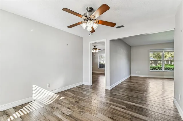 a view of an empty room with wooden floor and a window