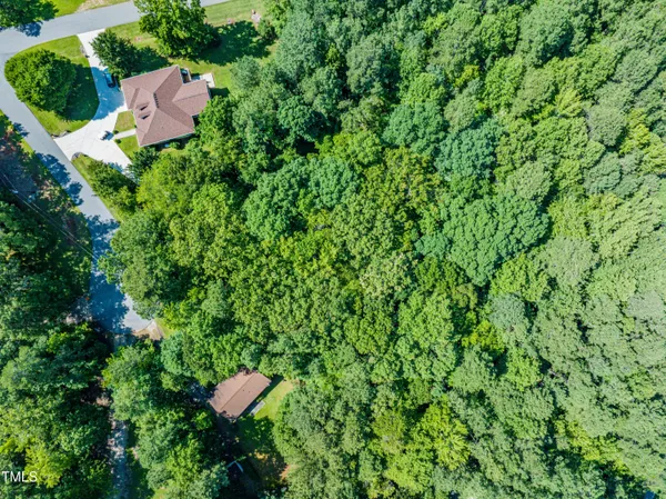 an aerial view of residential house with outdoor space and trees all around