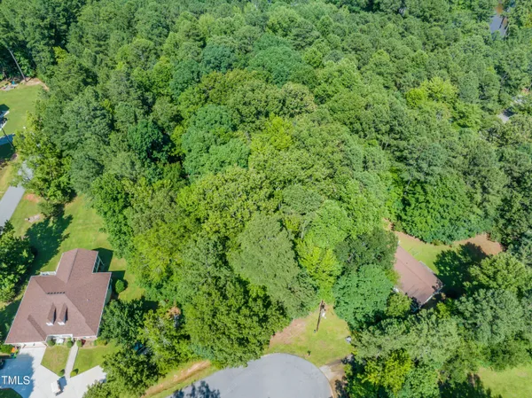 an aerial view of residential house with outdoor space and trees all around