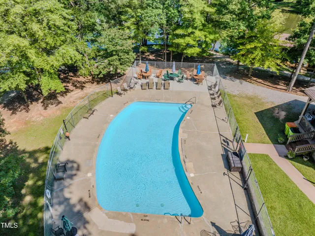an aerial view of a swimming pool with a yard and seating area