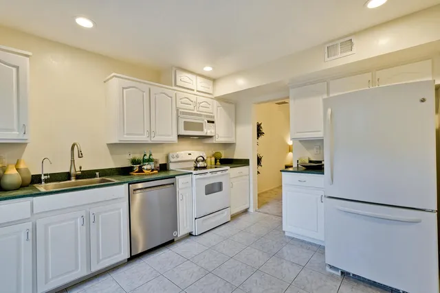 a kitchen with white cabinets and white appliances