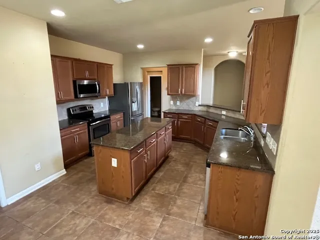 a kitchen with stainless steel appliances granite countertop a stove a sink a refrigerator and a microwave