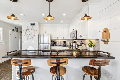 a kitchen with stainless steel appliances granite countertop a sink a stove and a wooden floor