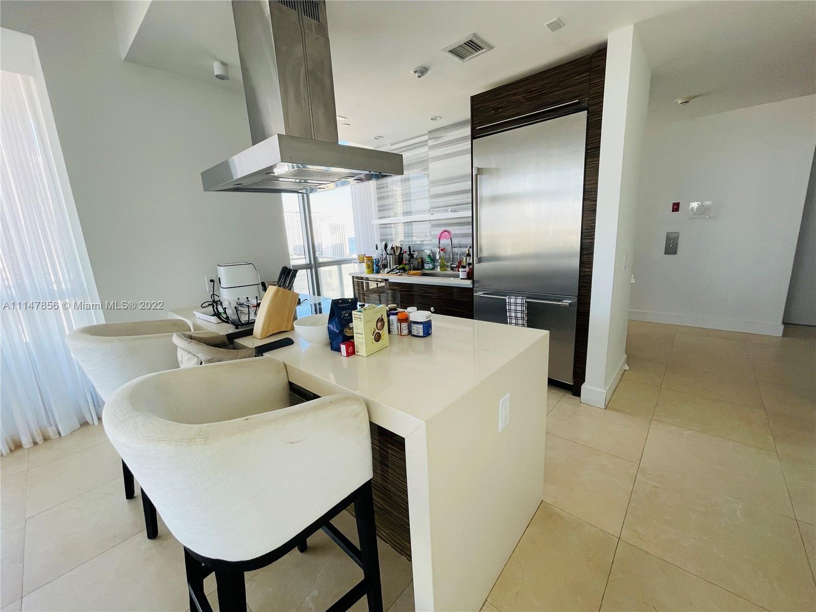 1100 Biscayne Boulevard, Unit 2003 Miami, FL 33132 - Photo 4 of 24 a kitchen with stainless steel appliances a table chairs and a refrigerator