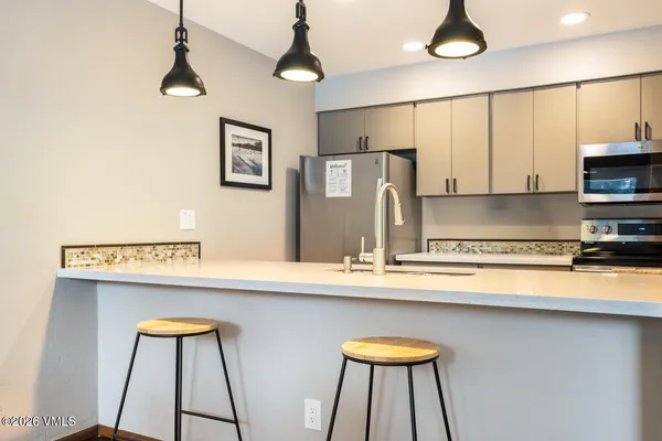 a kitchen with stainless steel appliances a sink a stove and a refrigerator with wooden floor