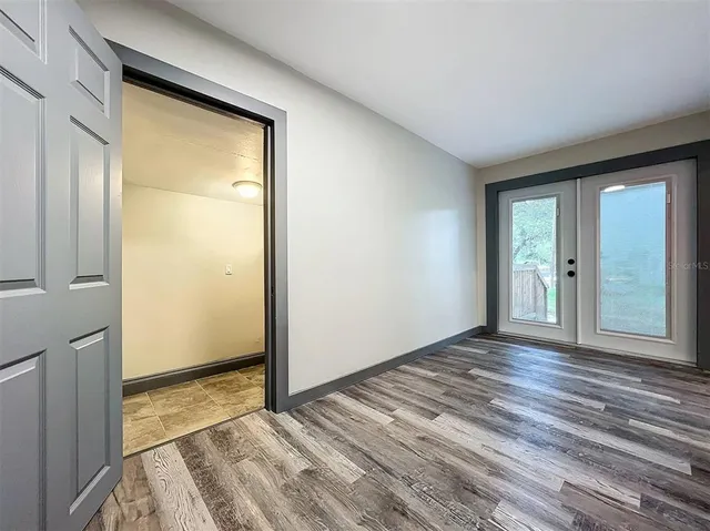 a view of an empty room with window and wooden floor