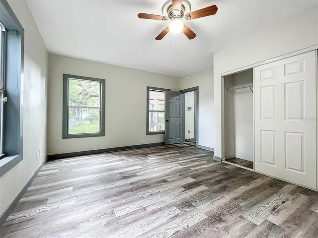 a view of an empty room with a window and a chandelier fan