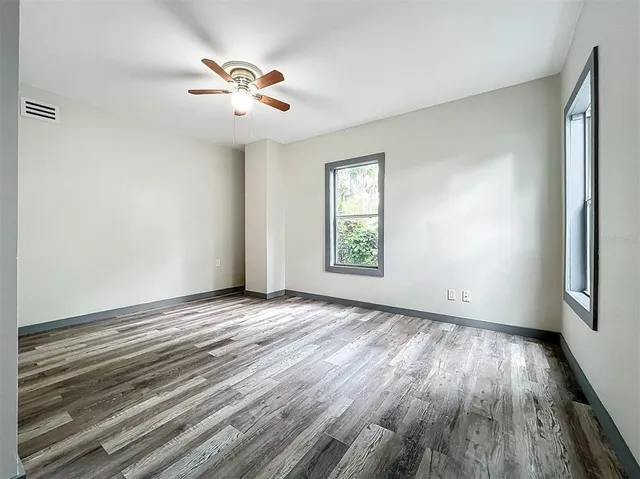a view of a hallway with wooden floor and a bathroom