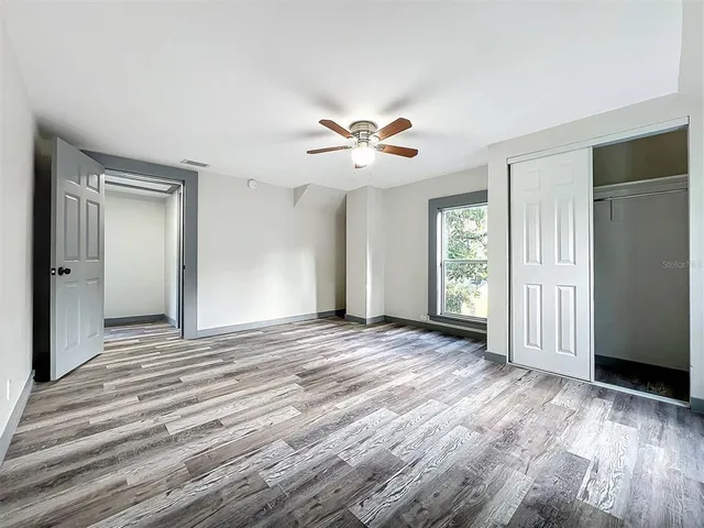 a view of a hallway with wooden floor and a bathroom