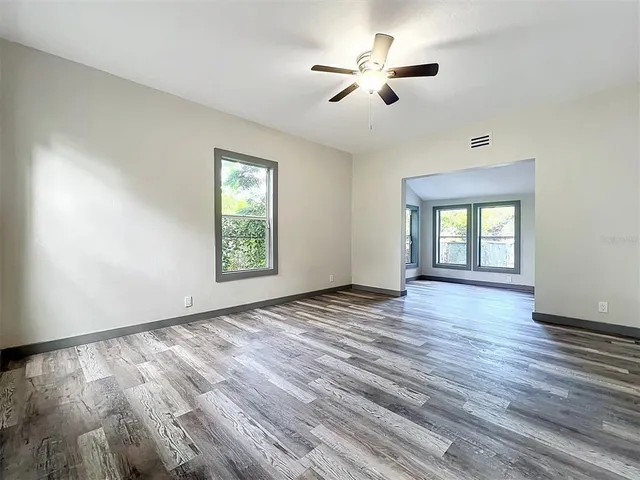 a view of an empty room with a window and wooden floor
