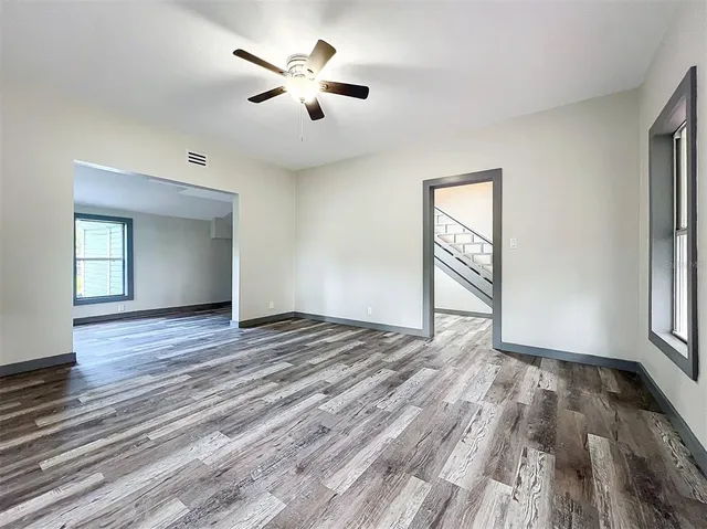 a view of an empty room with wooden floor and a window