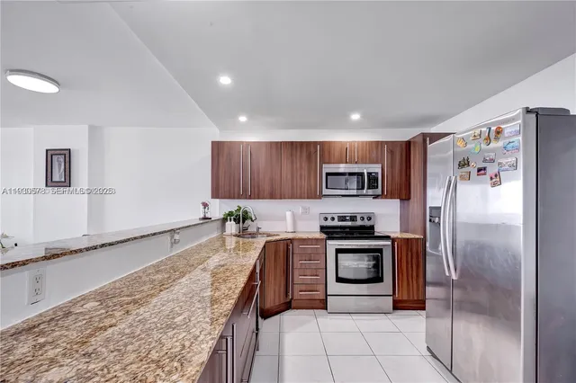 a kitchen with stainless steel appliances granite countertop a refrigerator a stove and a sink