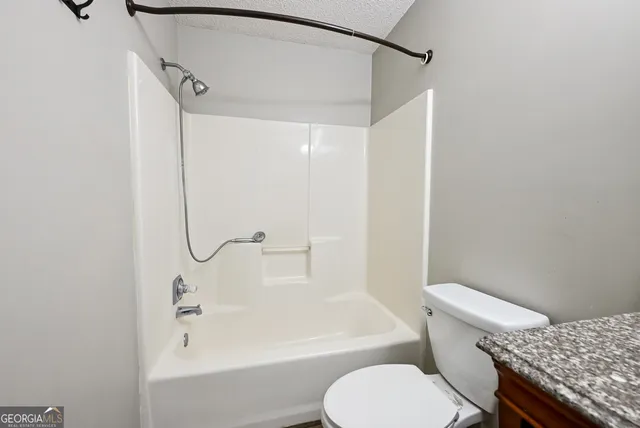 a bathroom with a granite countertop bathtub shower sink and toilet