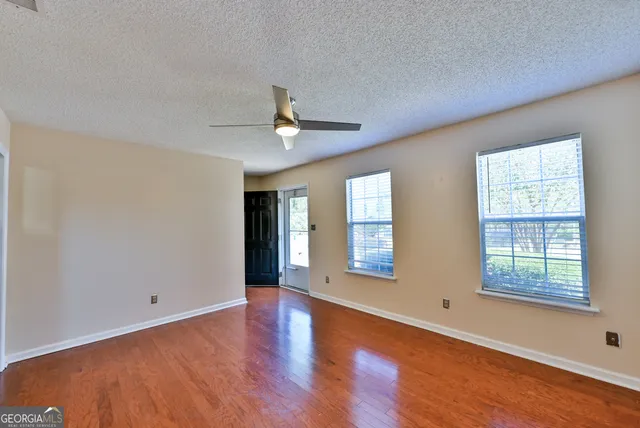 a view of an empty room with a window and wooden floor