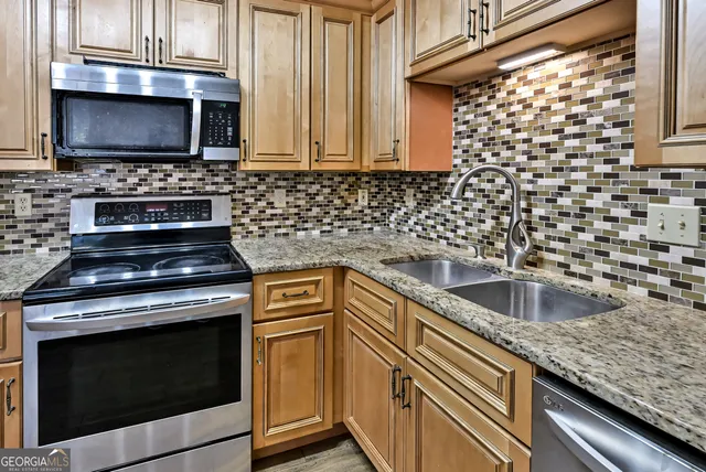 a kitchen with granite countertop a stove sink and microwave
