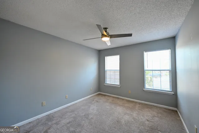 an empty room with a window and a fan