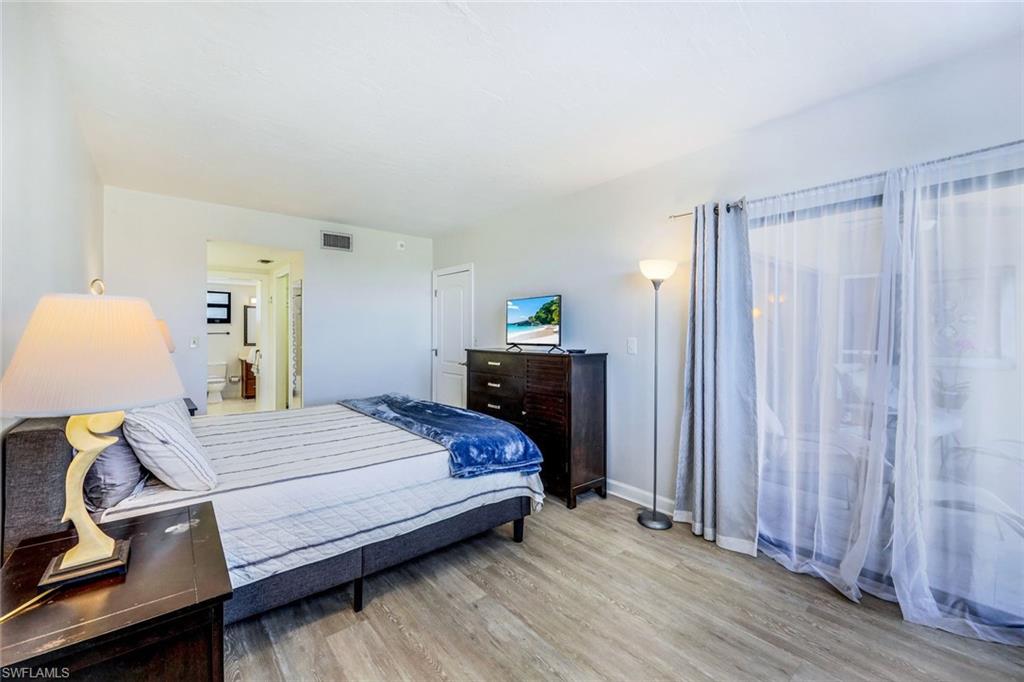 803 River Point Drive, Unit 201B Naples, FL 34102 - Photo 14 of 21 a bedroom with a bed and a chandelier