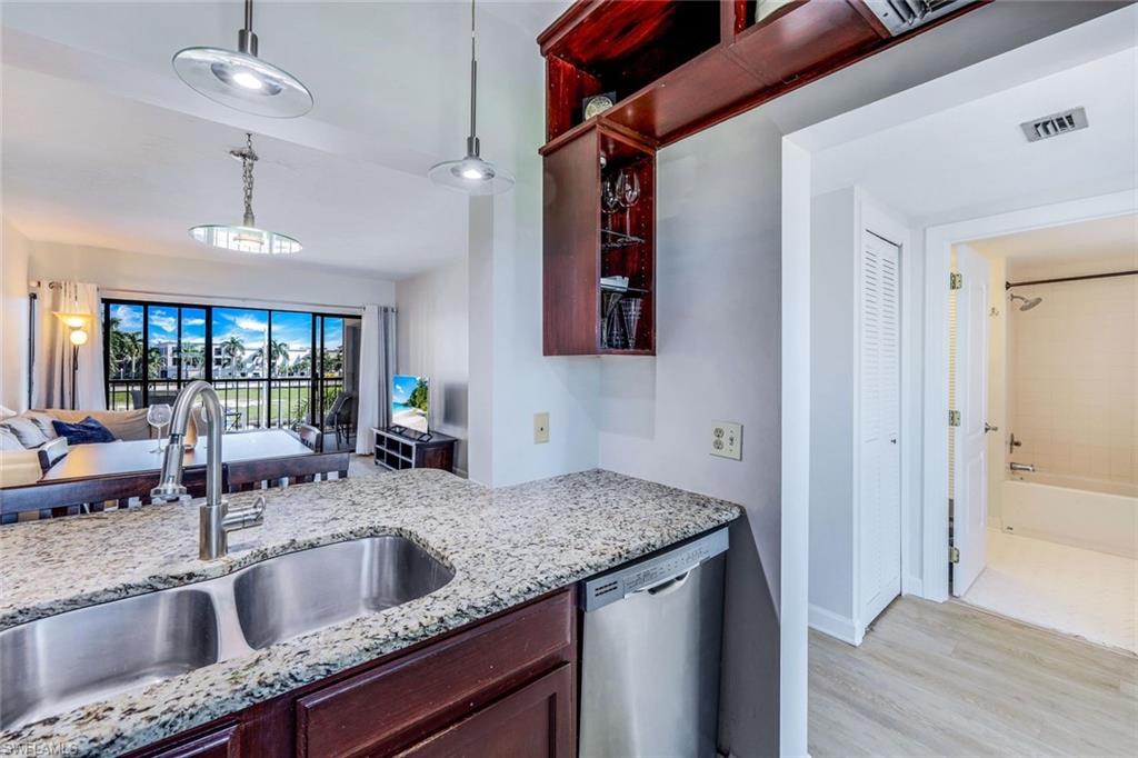 803 River Point Drive, Unit 201B Naples, FL 34102 - Photo 5 of 21 a view kitchen with granite countertop a sink and dishwasher with wooden floor
