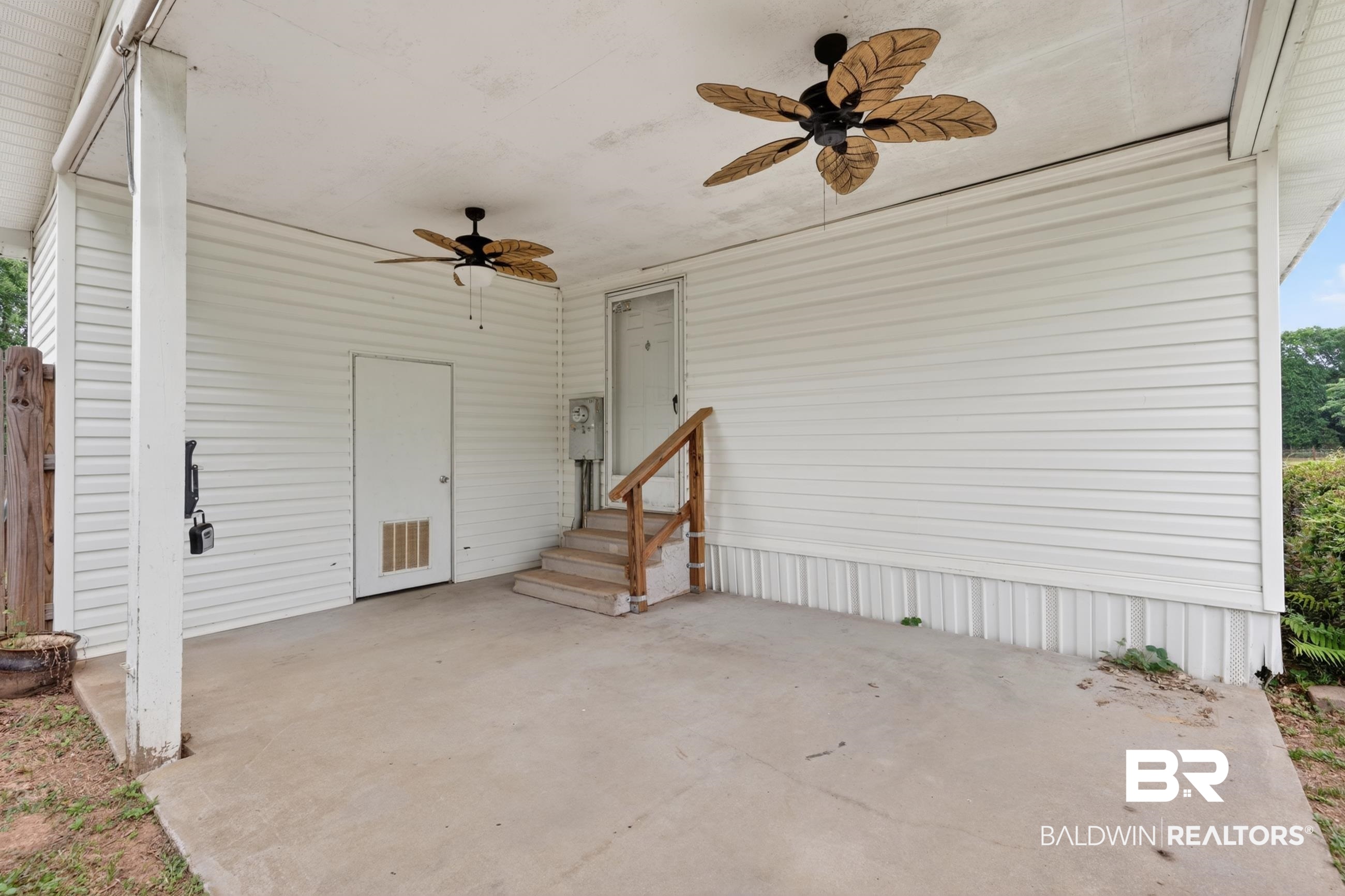 24903 Patterson Road Robertsdale, AL 36567 - Photo 23 of 57 Covered outdoor patio featuring a concrete surface, white siding, and two ceiling fans with leaf-style blades