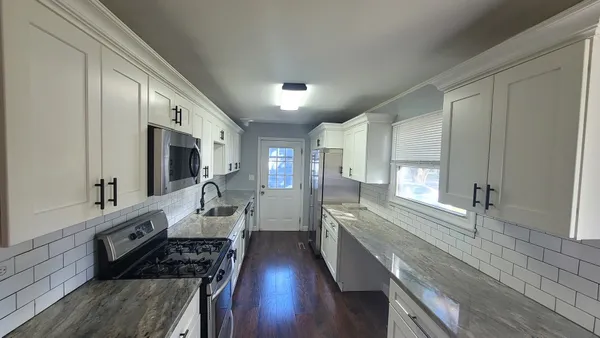 a large kitchen with stainless steel appliances a lot of counter space and a wooden floor