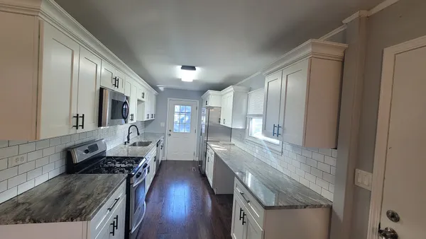 a large kitchen with stainless steel appliances granite countertop a lot of counter space and wooden floor