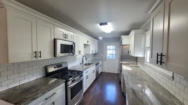 a large kitchen with stainless steel appliances granite countertop a lot of counter space and wooden floor