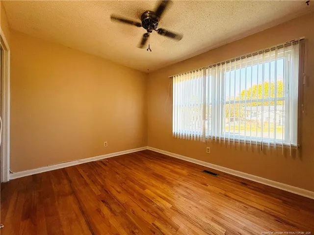 a view of an empty room with a window and wooden floor