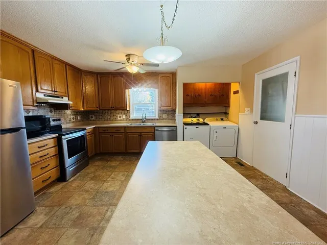 a kitchen with stainless steel appliances granite countertop a sink dishwasher stove top oven a refrigerator with island and chairs