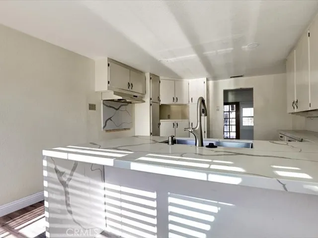 a view of a kitchen with kitchen island a sink stainless steel appliances and cabinets