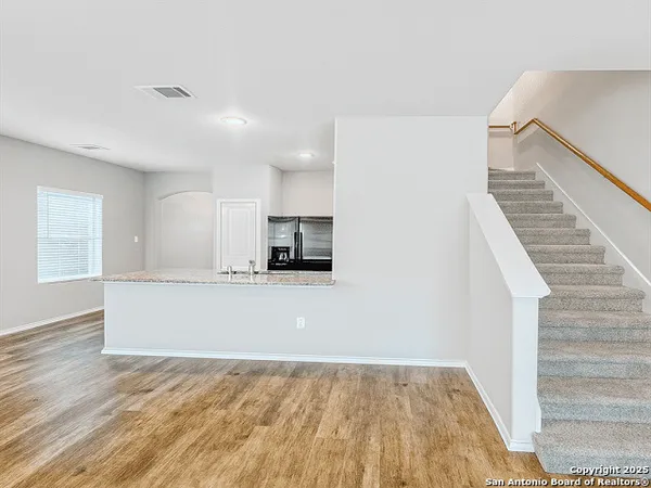 a view of kitchen and empty room with wooden floor