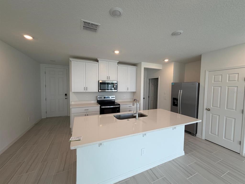 4256 Ranch House Road St. Cloud, FL 34772 - Photo 3 of 30 a kitchen with stainless steel appliances a refrigerator sink and microwave