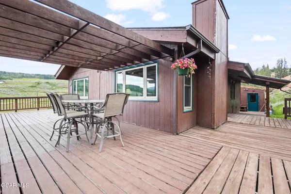 a view of a roof deck with table and chairs under an umbrella with wooden floor