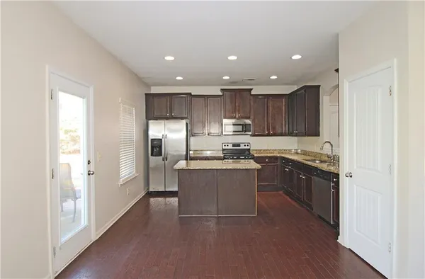 a large kitchen with stainless steel appliances granite countertop a refrigerator and a stove top oven