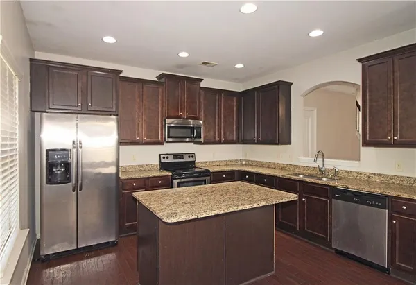 a kitchen with stainless steel appliances granite countertop a refrigerator a sink a stove a microwave and island