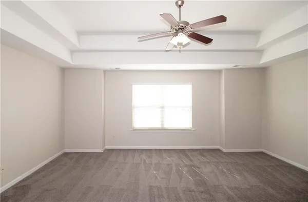 an empty room with a chandelier fan and windows