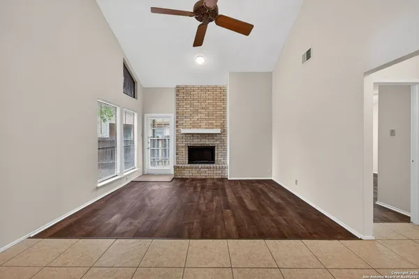 a view of an empty room with wooden floor fireplace and a window