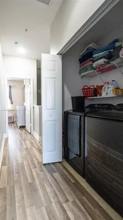 a view of a hallway to room with wooden floor and cabinets