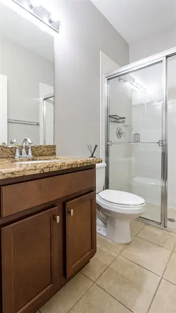 a bathroom with a granite countertop sink toilet a mirror and shower