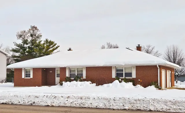 a front view of a house with a yard covered in snow