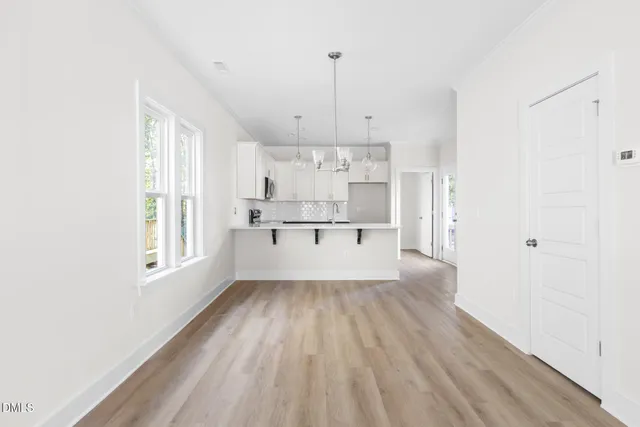 a view of a kitchen with kitchen island a sink wooden floor and white appliances