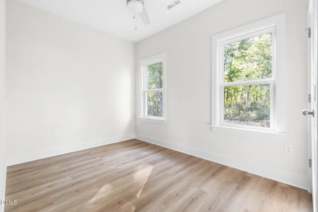an empty room with wooden floor and windows